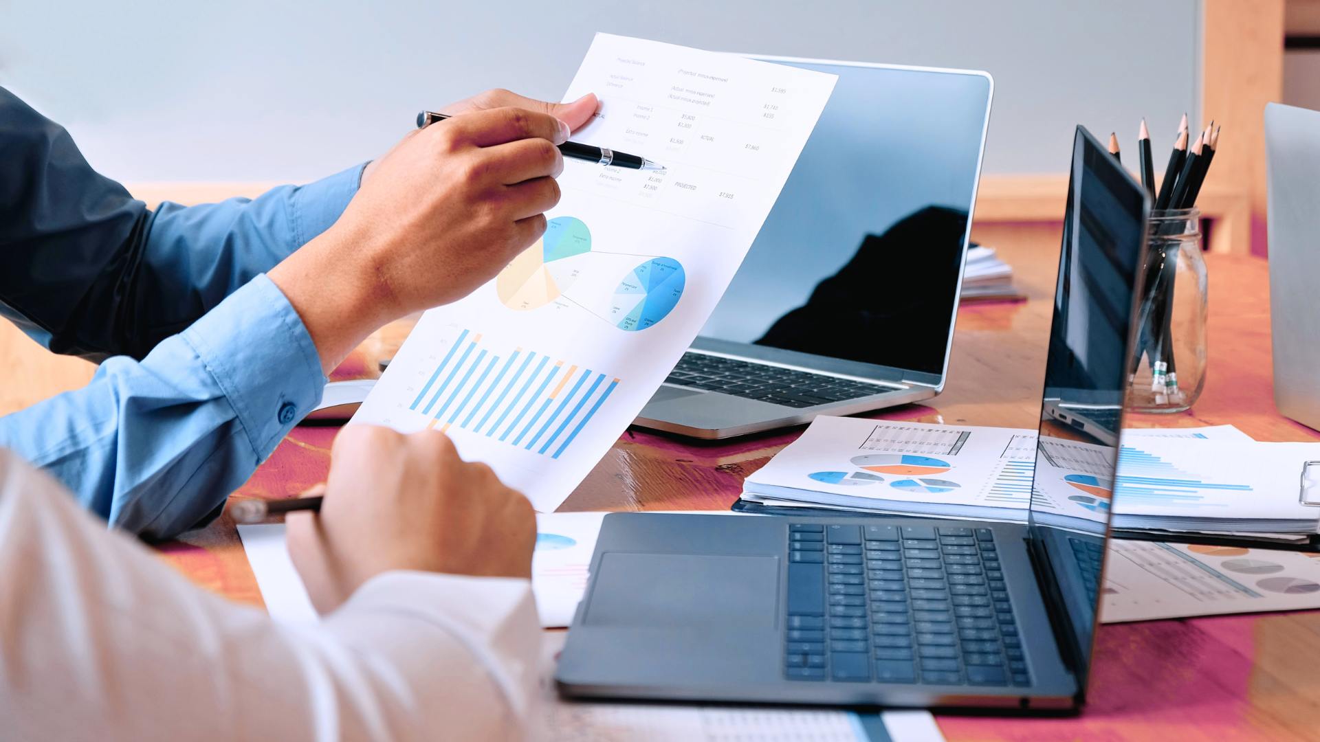 Analisi di report finanziari e grafici di performance aziendale su carta e laptop